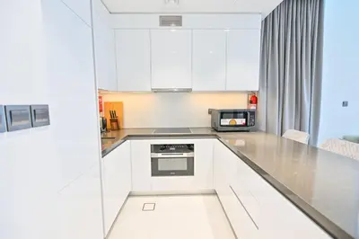 a kitchen with white cabinets and a microwave at Luxury and Spacious 1 Bedroom in District One Meydan in Dubai