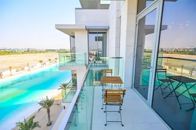 a balcony with chairs and a swimming pool on a building at 1BR Escape by the Lagoon in District One Meydan in Dubai