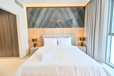 a bedroom with a large bed with white sheets at 1BR Retreat by the Crystal Lagoon in District One Meydan in Dubai
