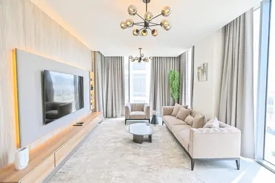a living room with a couch and a tv at 1BR Retreat by the Crystal Lagoon in District One Meydan in Dubai