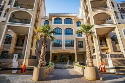 a building with palm trees in front of it at Bright 1Bdr at Fortunato in Dubai