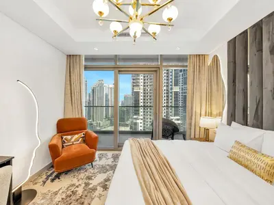 a bedroom with a bed and a chair and a large window at Luxury Apartments at Paramount Midtown by Dale Lee in Dubai