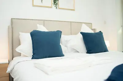 a bed with blue and white pillows on it at AWS Holiday Homes - Stylish Gem in the Palm in Dubai