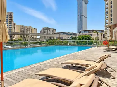 a swimming pool with chaise lounge chairs on a building at AWS Holiday Homes - Stylish Gem in the Palm in Dubai