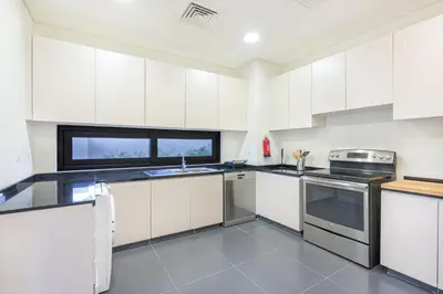 a kitchen with white cabinets and a stove top oven at Gorgeous 3BR Townhouse with Private Garden in Dubai