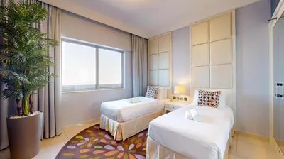 a hotel room with two beds and a potted plant at The Signature - Two Bedroom in Downtown Dubai in Dubai