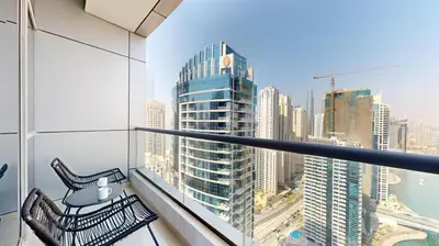 a balcony with two chairs and a view of a city at Bay Central 1 - One Bed with Stunning Marina View in Dubai