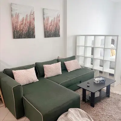 a living room with a green couch and a table at Fully Furnished Marina View - 1 Bedroom Apartment in Dubai