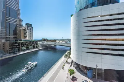 a boat in a river next to a building at Stayis -Studio in Twisted Tower Dubai Marina in Dubai