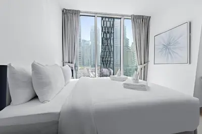 a bedroom with a white bed with a large window at Stayis -Studio in Twisted Tower Dubai Marina in Dubai
