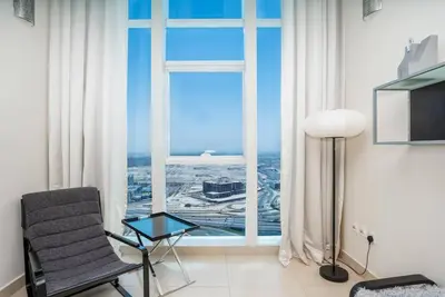 a living room with a chair and a window at Duplex Suite in 5-Star Movenpick Hotel in Dubai