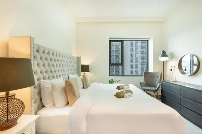 a bedroom with a large white bed and a chair at Nicely Furnished 2BR Home in Dubai Hills in Dubai