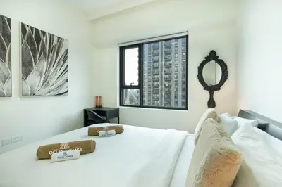 a white bedroom with a bed with a mirror at Nicely Furnished 2BR Home in Dubai Hills in Dubai