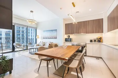 a kitchen and living room with a wooden table and chairs at Nicely Furnished 2BR Home in Dubai Hills in Dubai