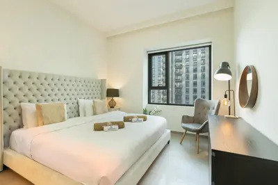 a white bedroom with a large bed and a desk at Nicely Furnished 2BR Home in Dubai Hills in Dubai