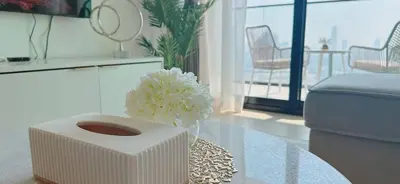 a white vase with flowers on a table in a living room at Bright & Cozy 1br Jvc Balcony Free Parking in Dubai