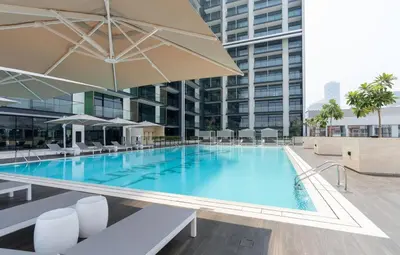 a large pool with chairs and umbrellas in a building at Bright & Cozy 1br Jvc Balcony Free Parking in Dubai