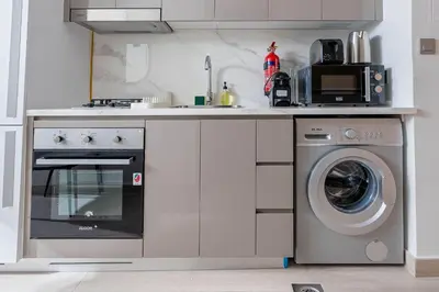 a kitchen with a washer and a washing machine at Nasma Luxury Stays - Trendy & Stylish Living Studio at Azizi Riviera 41 in Dubai