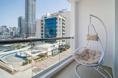 a swinging chair on a balcony with a view of a city at Frank Porter - DEC Tower 3 in Dubai