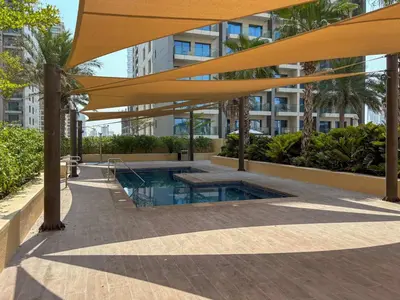 a swimming pool in a building with a large yellow umbrella at Frank Porter - Damac Ghalia Tower - Studio in Dubai