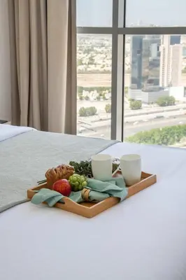 a tray of fruit and vegetables on a bed with two cups at Frank Porter - Damac Ghalia Tower - Studio in Dubai
