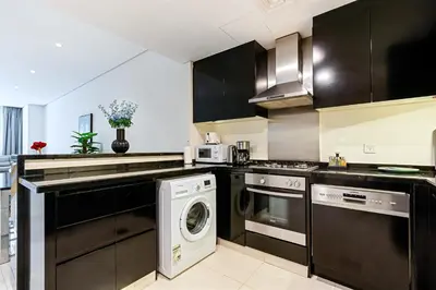 a kitchen with black cabinets and a washer and dryer at 3BR Apartment in Business Bay with Pool & Canal Walk in Dubai