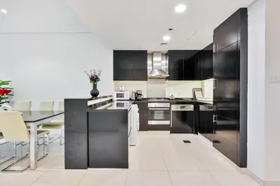 a kitchen with black cabinets and a table at 3BR Apartment in Business Bay with Pool & Canal Walk in Dubai