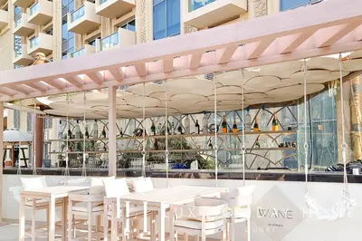 a restaurant with white tables and chairs in front of a building at LUX The JW Marina Studio 3 in Dubai
