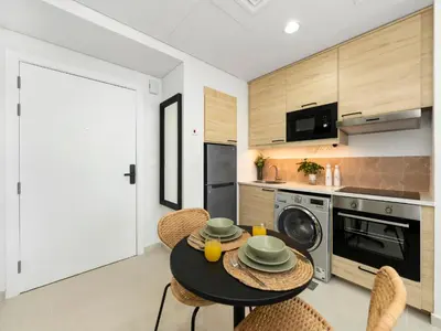 a kitchen with a table and chairs and a microwave at Dar Mama - Cozy modern apartment in Golf Vita, Dubai in Dubai