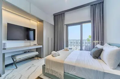 a bedroom with a large bed with a flat screen tv at Chic and Bright Studio in Meydan in Dubai