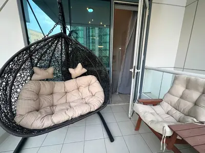 a hammock chair and a couch on a balcony at 2 Bedrooms Apartment with Marina Views in Dubai