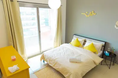 a bedroom with a bed with yellow pillows and a window at Himalaya Holiday Homes 1 BHK Apartment in Dubai
