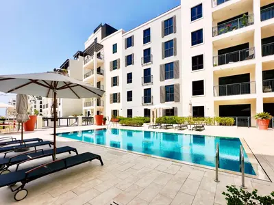 a swimming pool with two chairs and an umbrella next to a building at La Cote, Port de La Mer, Jumeirah 1 - Mint Stay in Dubai