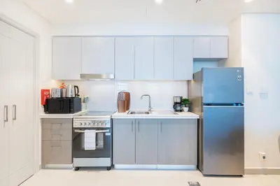 a kitchen with white cabinets and a blue refrigerator at Minimal 1BR Minutes away from the Dubai Mall in Dubai
