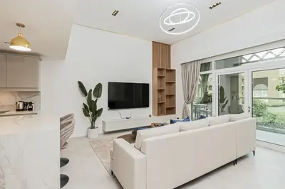 a white living room with a white couch and a tv at Luxury at Beachside Al Sultana Jumeirah Shoreline - DVH Holiday Homes in Dubai
