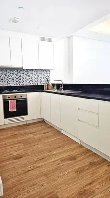 a kitchen with white cabinets and a wooden floor at Luxury 2BR Midtown Apartment in Dubai