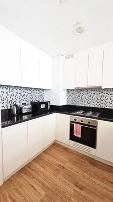 a kitchen with white cabinets and a stove top oven at Luxury 2BR Midtown Apartment in Dubai