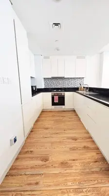 a kitchen with white cabinets and a wooden floor at Luxury 2BR Midtown Apartment in Dubai