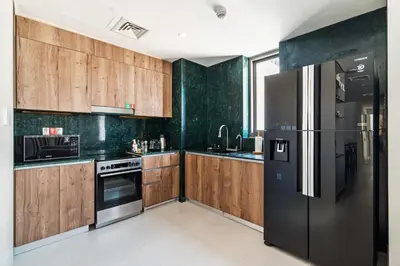 a kitchen with a black refrigerator and wooden cabinets at Luxury Apartment at Dubai Creek Harbour, Bayshore - By DuStay in Dubai