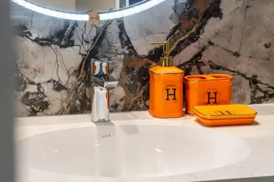a bathroom sink with a faucet and two orange containers at Luxury, Spacious Apartment in Dubai Creek Harbour - By DuStay in Dubai