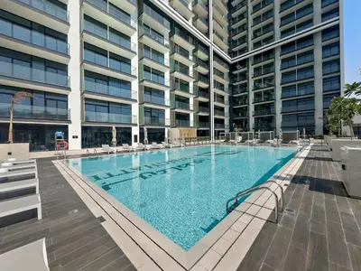 a large swimming pool in front of a building at Vayk - Modern 2BR Apartment in Dubai