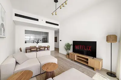 a living room with a white couch and a tv at Vayk - Modern 2BR Apartment in Dubai