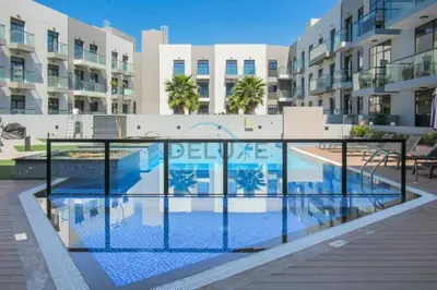 a swimming pool in front of a apartment building at Modern Loft-Style Studio at Aria Residence, Jumeirah Village Circle by Deluxe Holiday Homes in Dubai