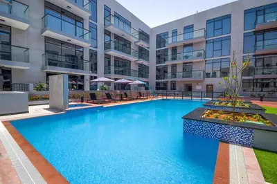 a swimming pool in front of a building at Modern Loft-Style Studio at Aria Residence, Jumeirah Village Circle by Deluxe Holiday Homes in Dubai