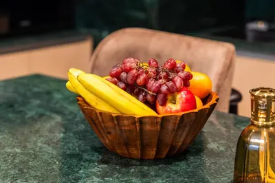 a basket of fruit on a table with a bottle at Elegant 2-Bedroom Apartment in Dubai Creek Harbour - By Dustay in Dubai
