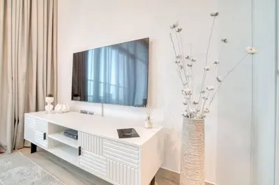a living room with a white dresser with a tv on it at 5 Mins to JBR Beach, Luxury Studio in Dubai Marina's Best Tower in Dubai