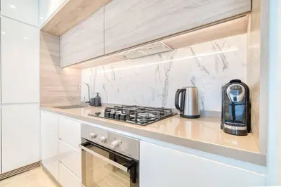 a kitchen with a stove top oven next to a counter at 5 Mins to JBR Beach, Luxury Studio in Dubai Marina's Best Tower in Dubai