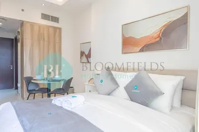 a bedroom with a bed and a table with chairs at Bloomfields Cozy Studio In Hera Tower Dubai in Dubai