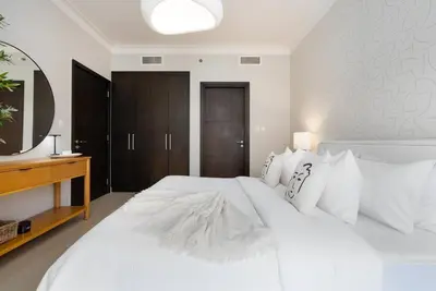 a bedroom with a large white bed with a mirror at Skyline Huge 1 Bedroom Apartment Creek in Dubai
