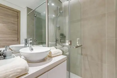 a bathroom with two sinks and a glass shower at Knokey Dubai Marina Comfortable Apartments with Pool and Gym in Dubai